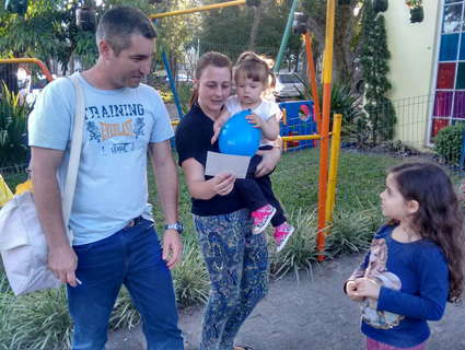 Momento em que as crian̤as entregaram adesivos do projeto para as famÌ_lias