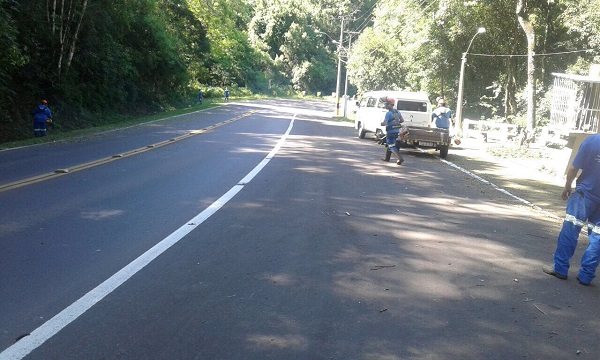 No Acesso Graasel, servidores trabalham roçando o entorno da via